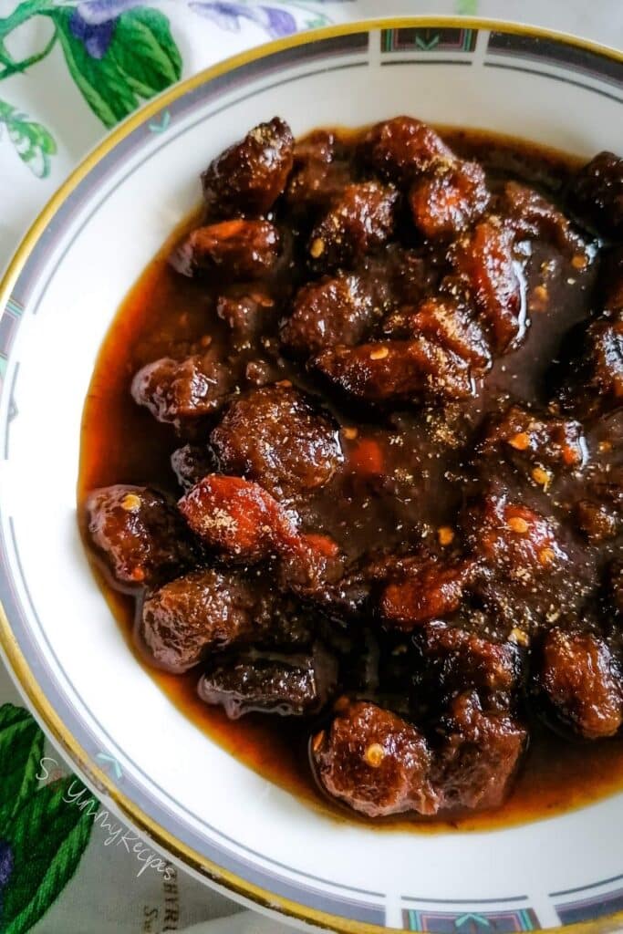Pakistani plum chutney - aloo bukhara in a round shallow bowl with gold rim.