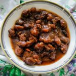 Plum chutney aloo bukhara in a gold rimmed shallow bowl.