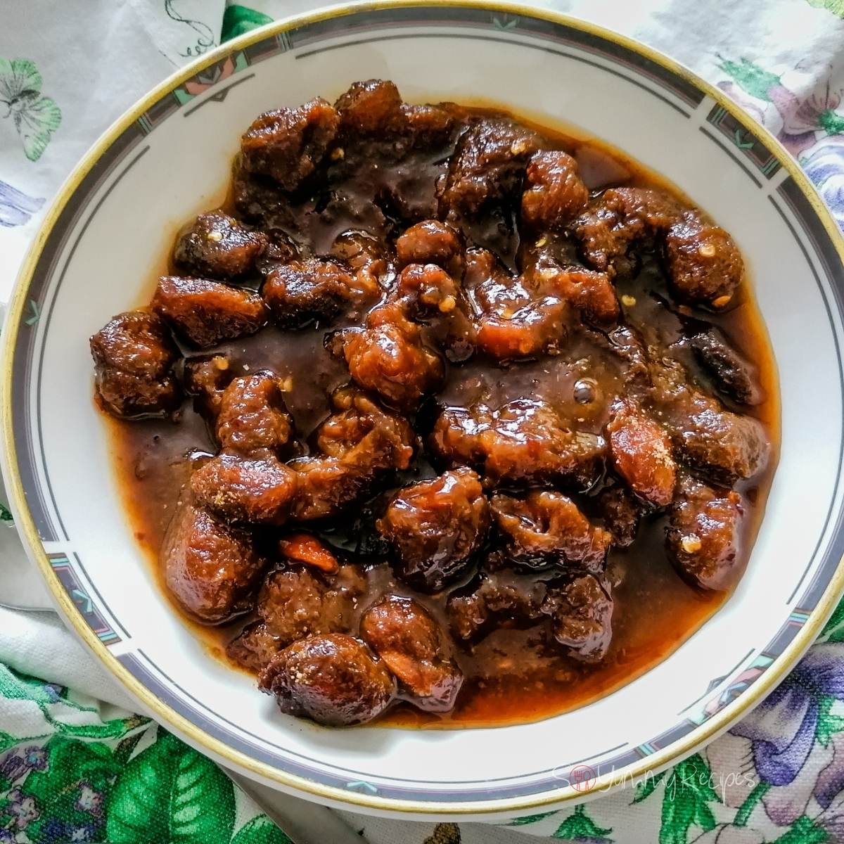 Plum chutney aloo bukhara in a gold rimmed shallow bowl.