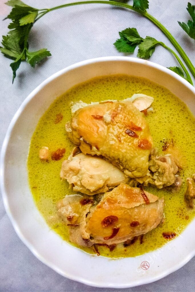 Opor Ayam in a round bowl with some parsley around it.