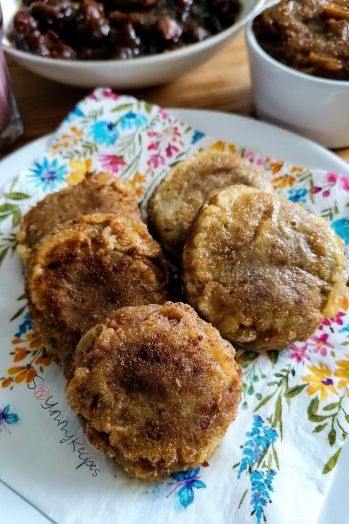 Five shami kebabs on a napkin with a few bowls of chutney on the background.