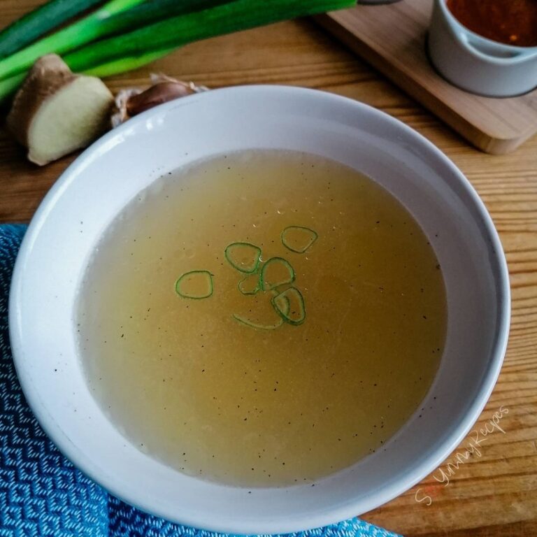 Chicken stock in a round white bowl.