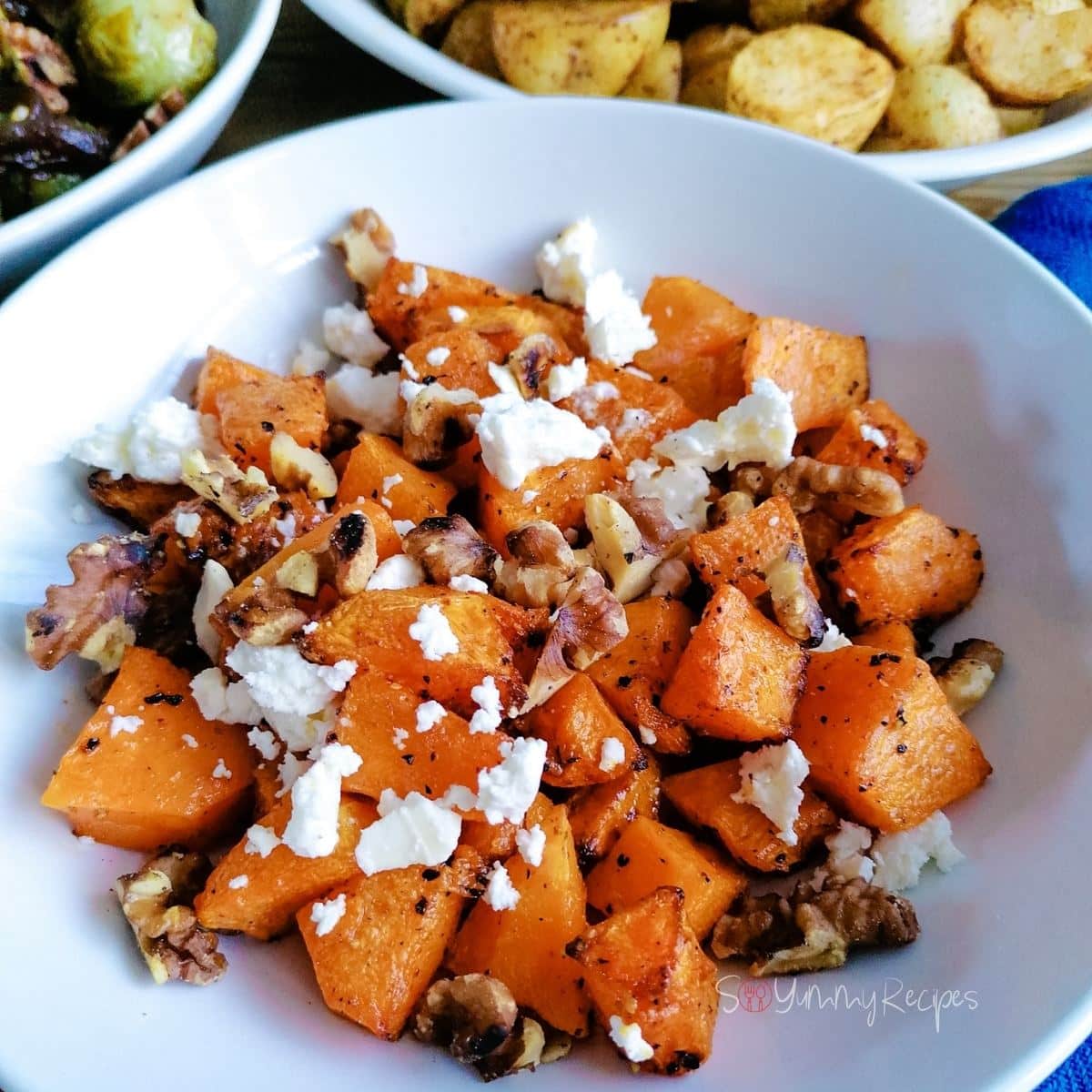 Air fried butternut squash with feta cheese on a white deep plate.