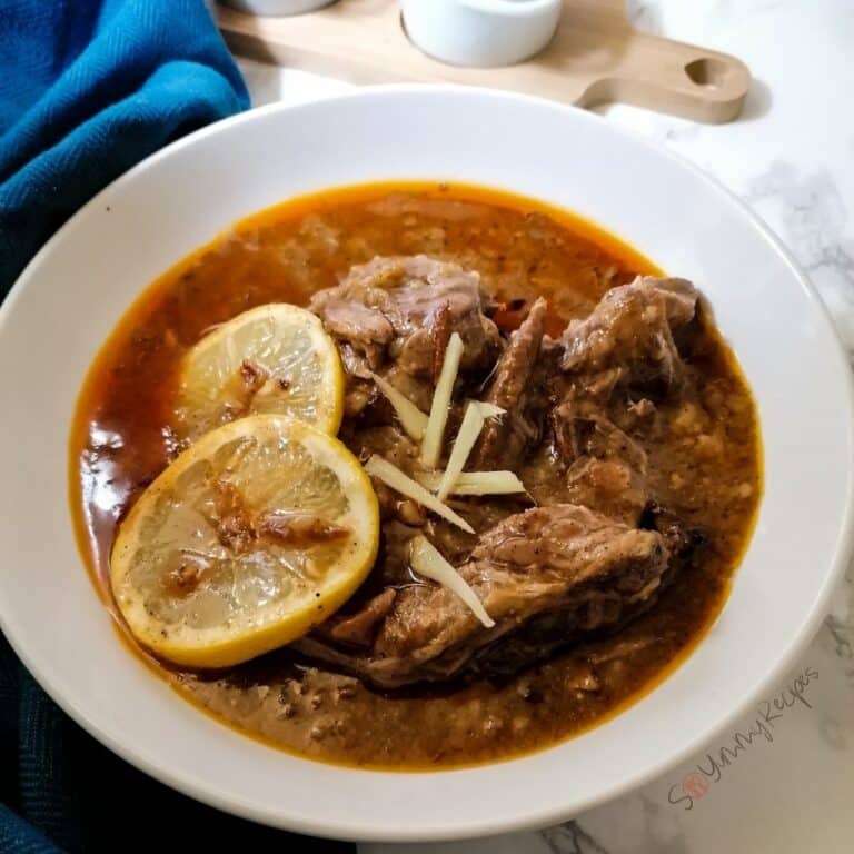 Pakistani lamb nihari garnished with sliced ginger and lemon.