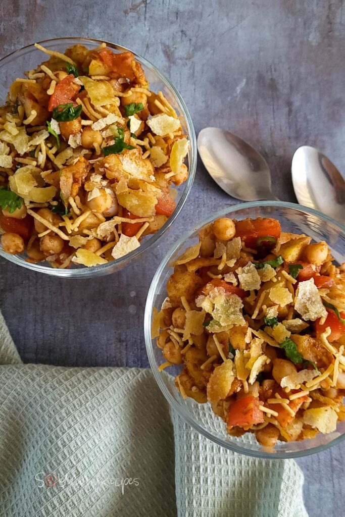 Two bowls of chana chaat with teaspoons and napkin on the background.