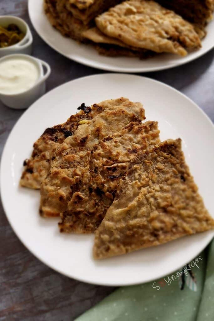 Four pieces of Keema Paratha on a white plate.