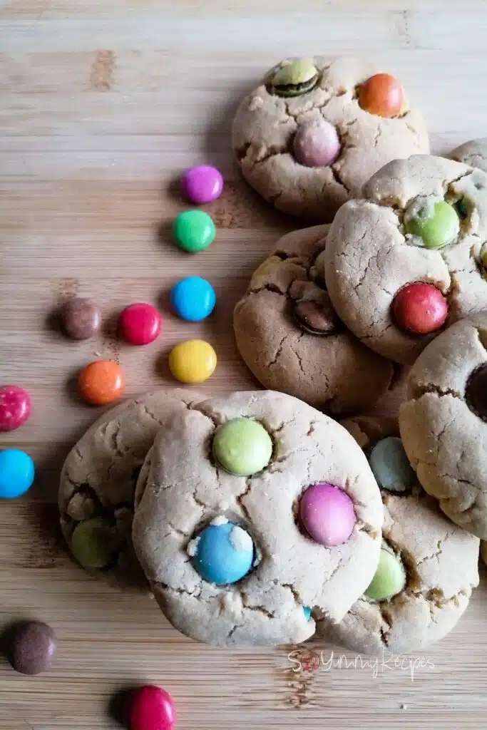 Some smarties cookies with some choclate smarties scattered around.