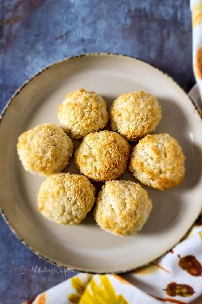 Seven coconut macaroons on a brown plate.