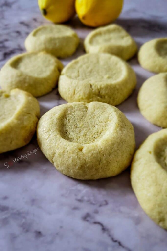 Rows of lemon shortbread cookies on a marble worktop.