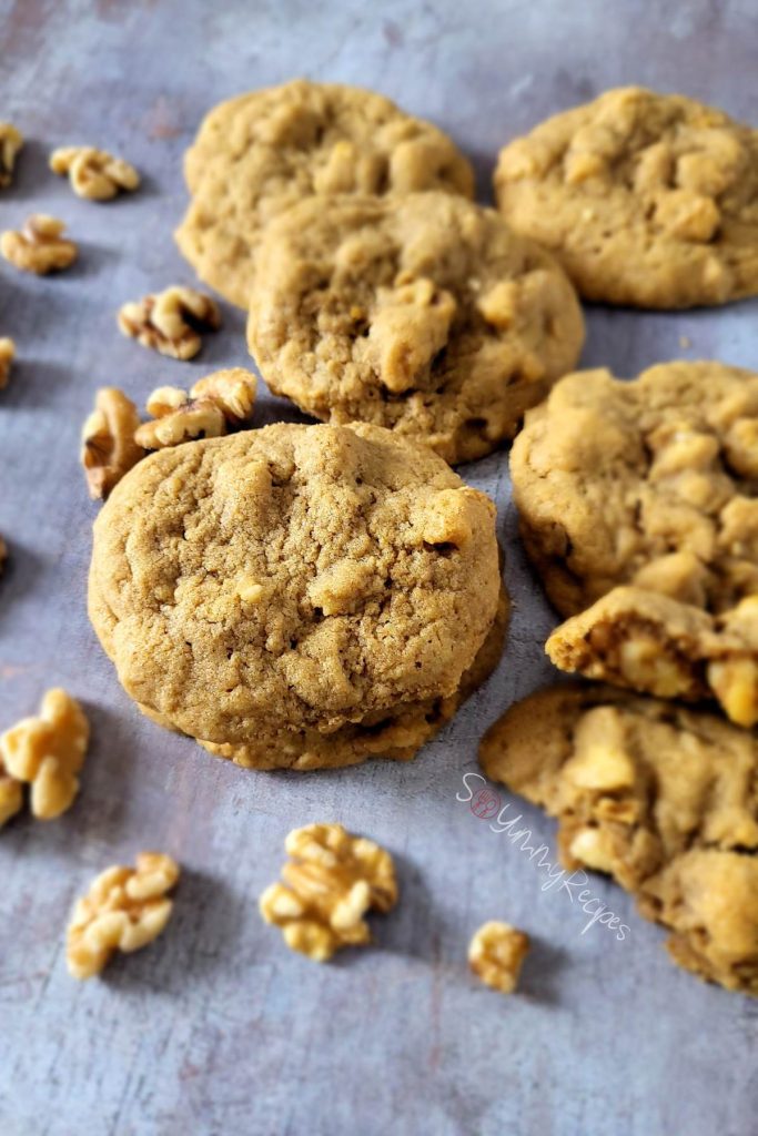 Coffee and walnut cookies with some scattered walnuts.