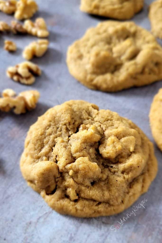 A piece of coffee walnut cookies with some in the background.