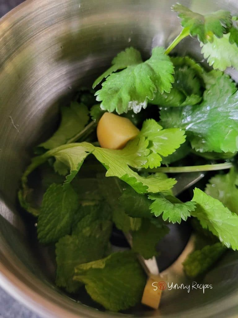 Cilantro, mint leaves and garlic inside a chopper.