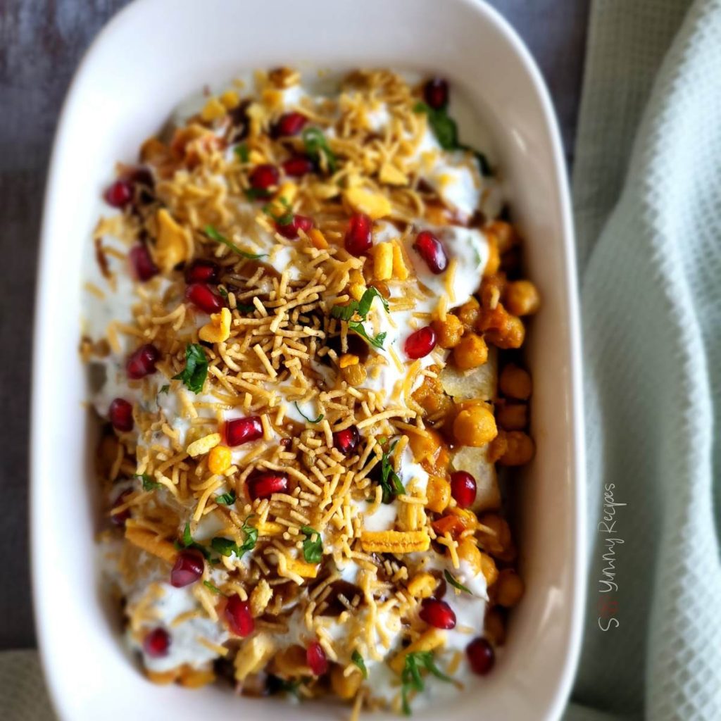 Samosa chaat in a white rectangle dish with light green napkin on the side.