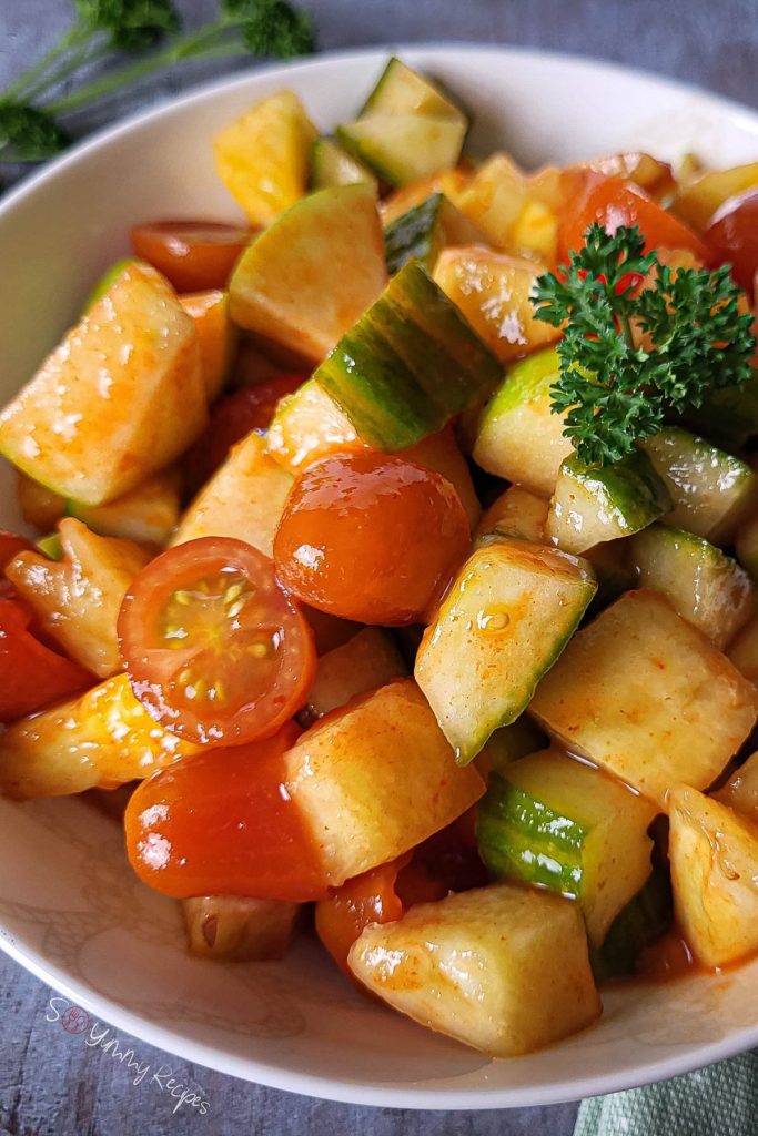 Tomato, cucumber, pineapple, and apple salad garnished with parsley.