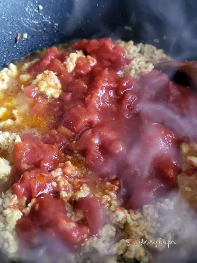 canned chopped tomatoes on cooked ground chicken.