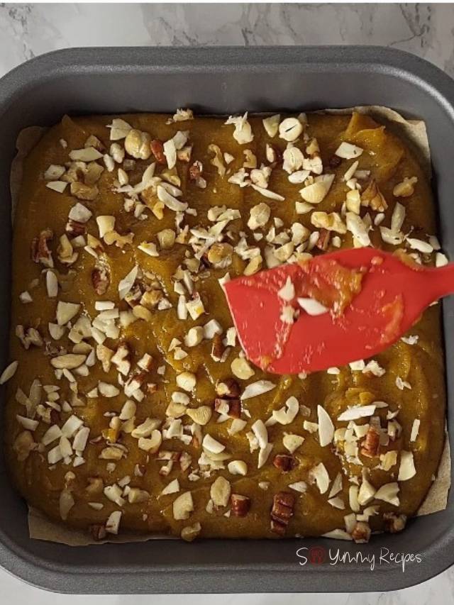 fudge with nuts on a baking pan and red spatula.