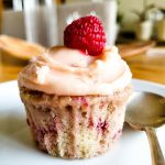 A raspberry cupcake with a spoon next to it.