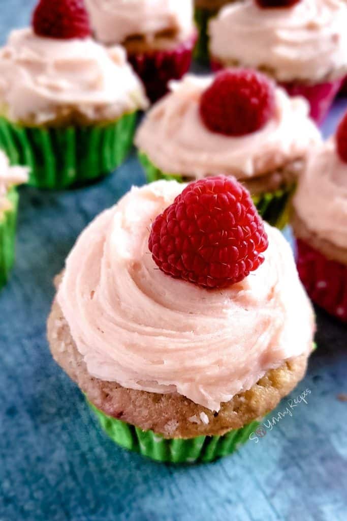 Cupcakes with raspberry buttercream and decorated with a raspberry on the top.