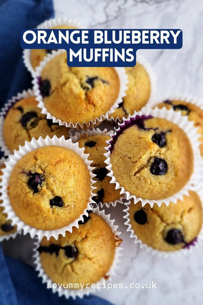 Stacked blueberry orange muffins on white marbled worktop.