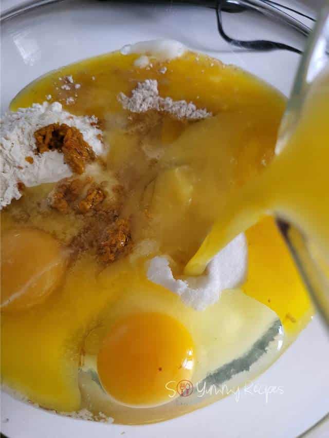 Pouring orange juice into muffin ingredients.