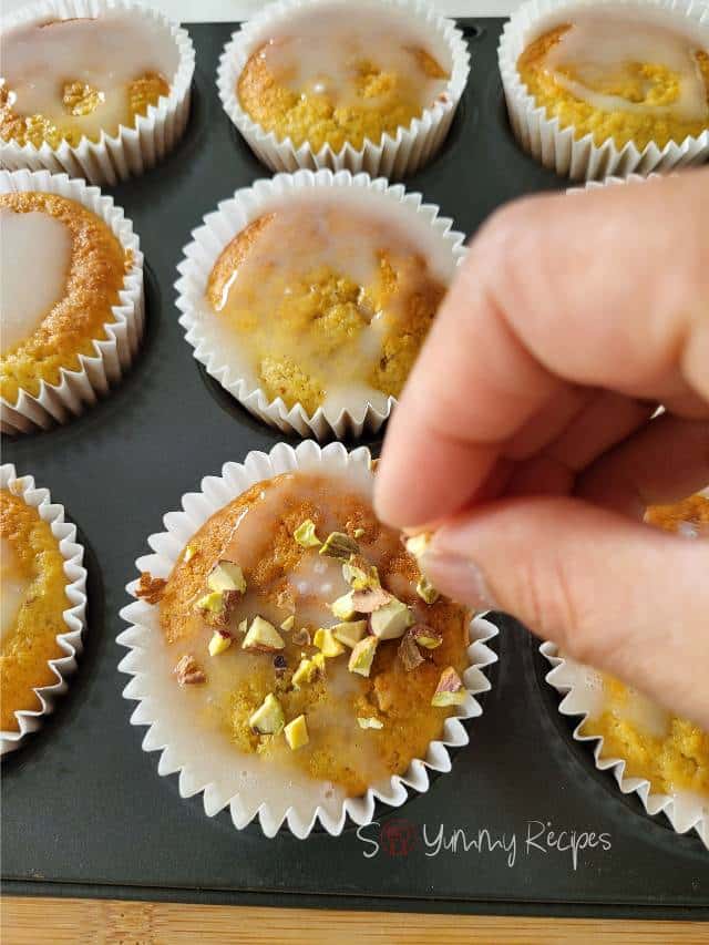 scatter some chopped pistachio nuts on muffins.