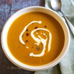 Pumpkin and sweet potato soup drizzled with cream.