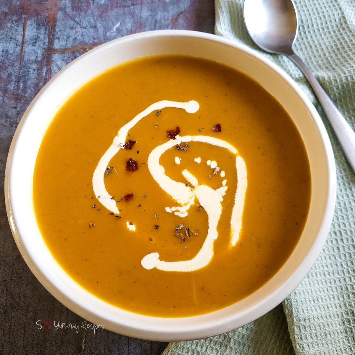 Pumpkin and sweet potato soup drizzled with cream.