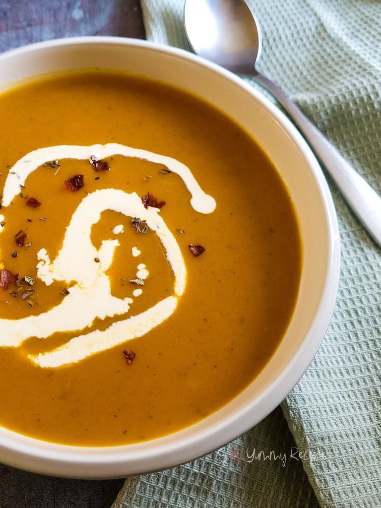 Blended soup of pumpkin and sweet potato drizzled with cream and sprinkled with red chili pepper flakes.
