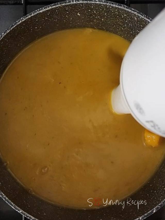 Blending the soup with a handheld blender.
