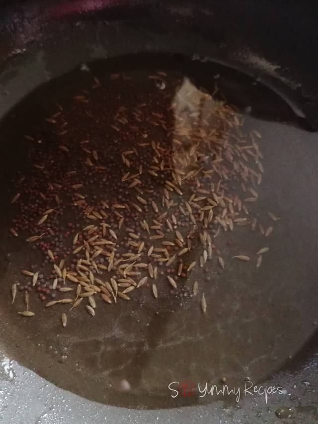 Whole cumin seeds and black mustard seeds in oil.