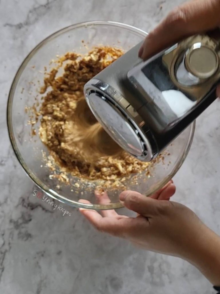Hand mixer over cake batter in a bowl.