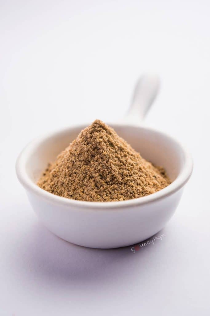 Chaat masala powder in a small white bowl with handle.