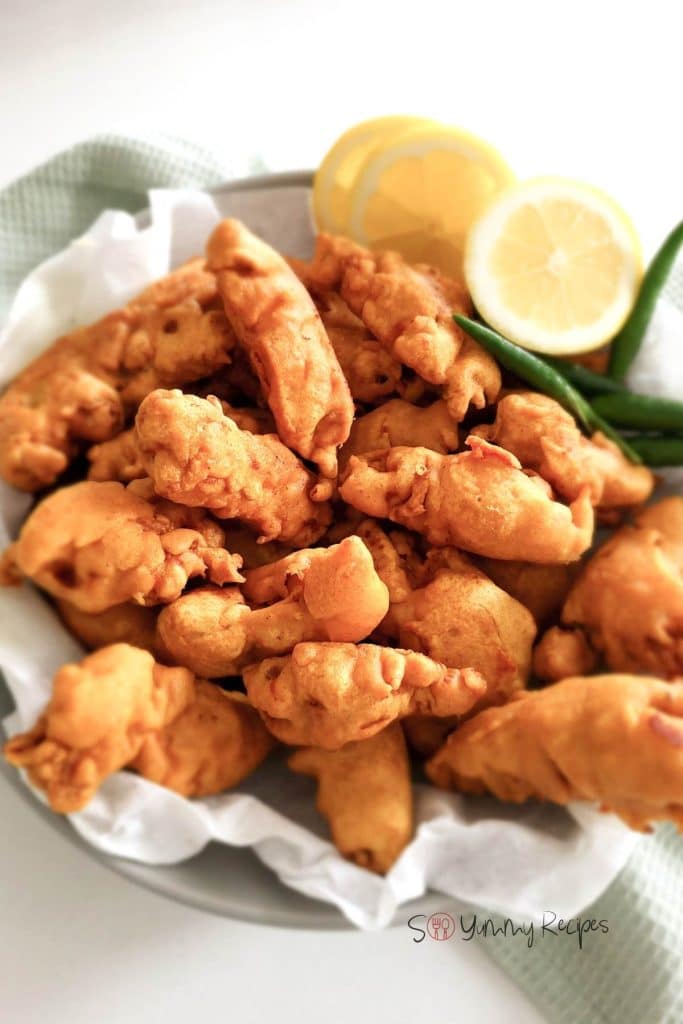 A plate of chicken pakora with green chilies and lemon slices.