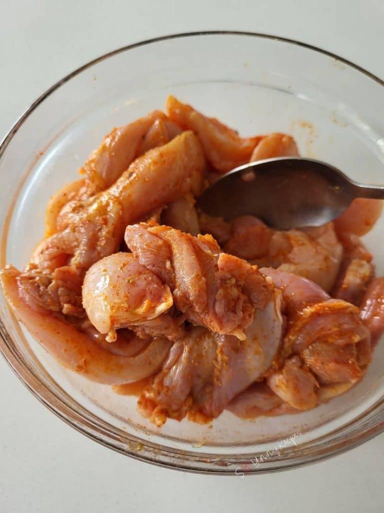 A bowl of chicken pieces coated in spices.