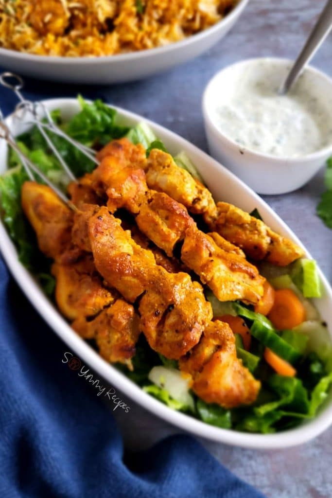 Chicken tikka skewers with yogurt chutney and biryani. 