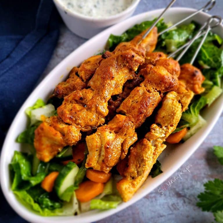 Chicken tikka kebabs on a bed of salad.