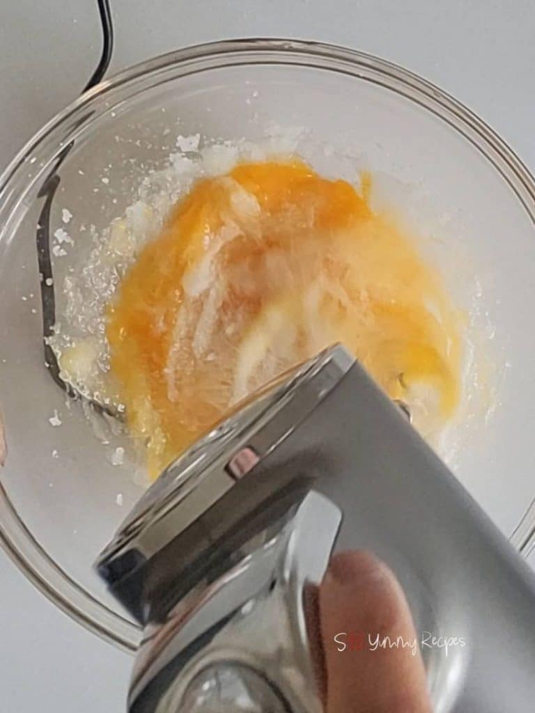 egg and sugar in a bowl with a mixer over it.