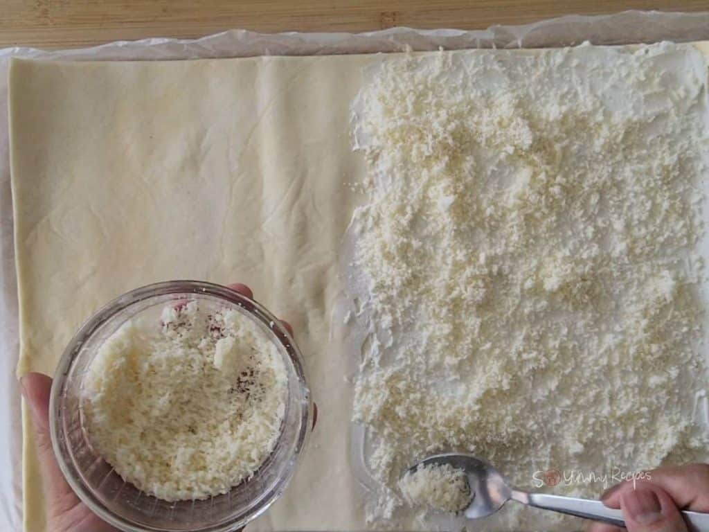 Grated cheese on a rolled-out puff pastry.