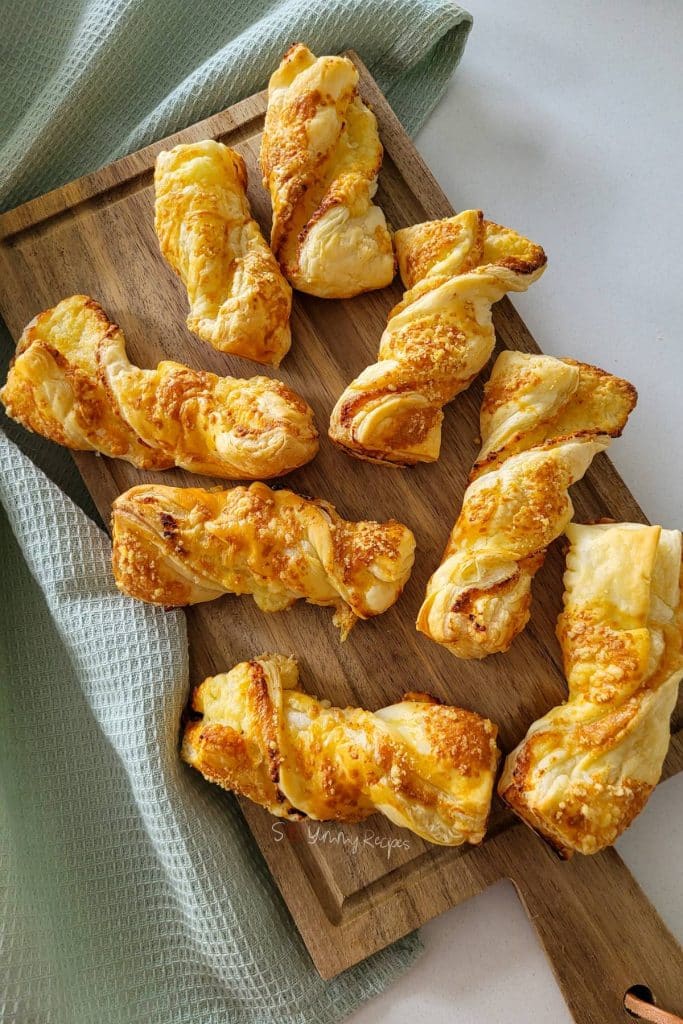 Cheese puff pastry straws on a chopping board.