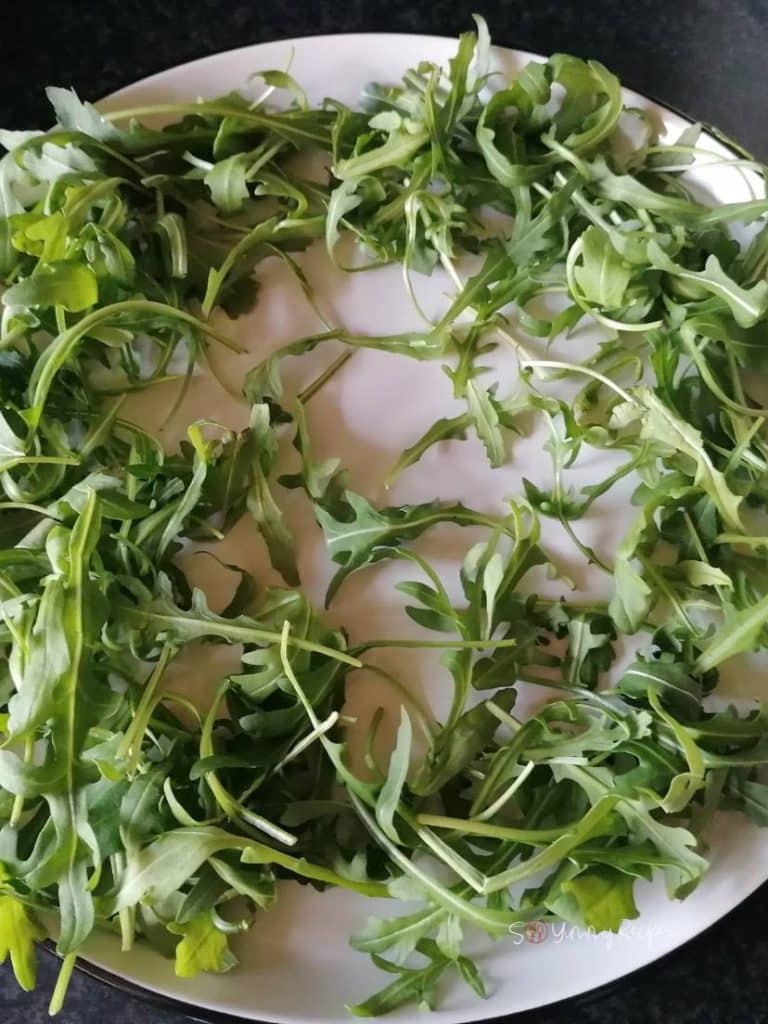 Arugula leaves on a white plate.