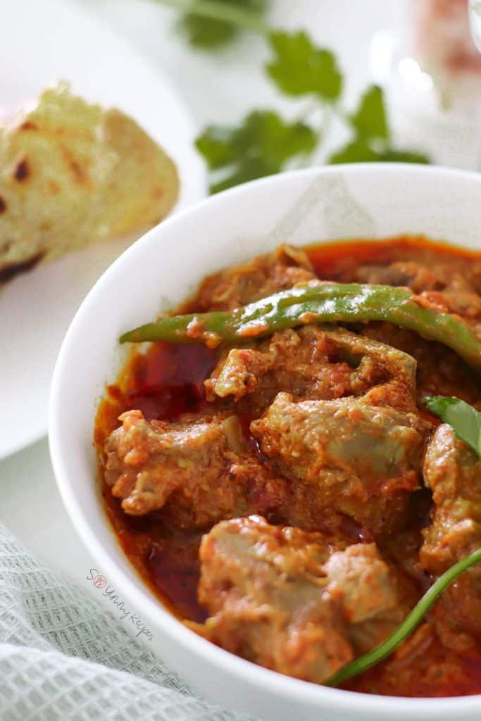 Pakistani lamb karahi in white bowl with chapati in the background.