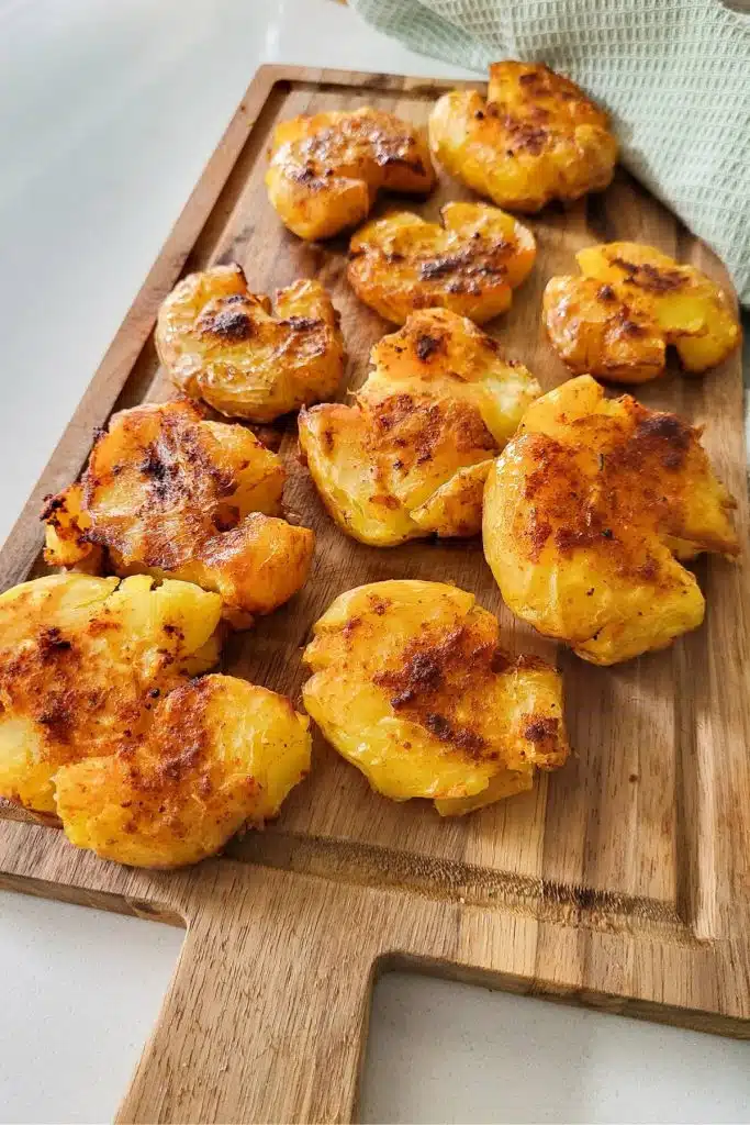 Smashed potatoes on a chopping board.