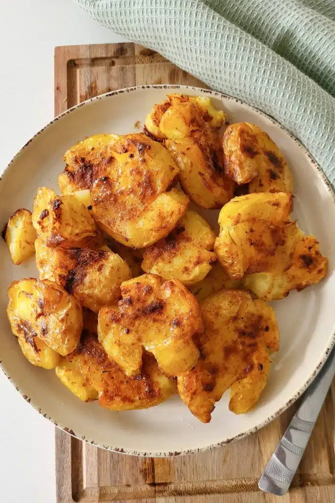 Air fried potatoes on a round plate with mint green napkin next to it.