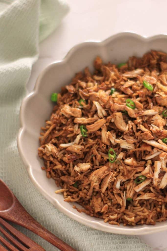 Indonesian nasi goreng ayam with mint napkin and wooden spoon in the background.