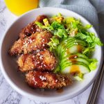 Chicken katsu bowl with sliced cucumber and lettuce.