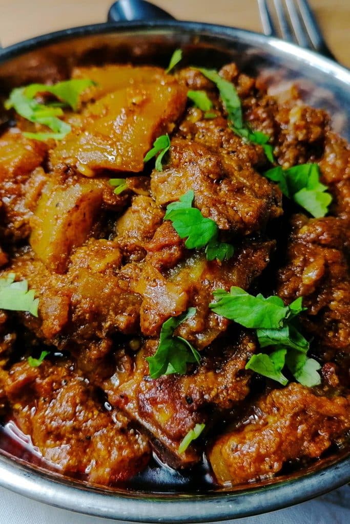 Dry meat curry with bottle gourd garnished with chopped cilantro.