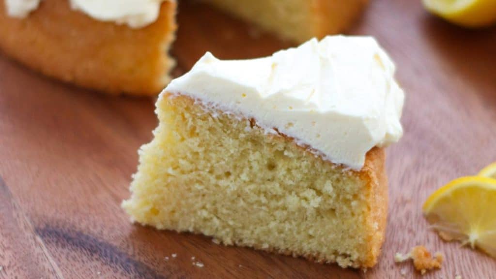 A slice of lemon curd cake with cream frosting.