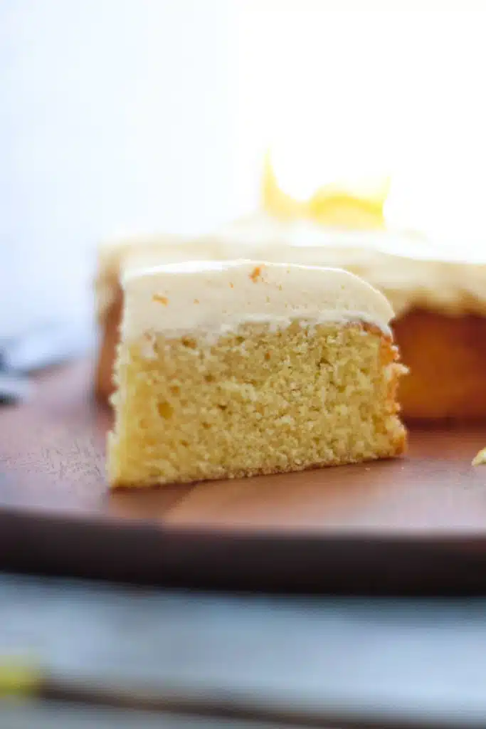 A piece of lemon curd cake on a wooden chopping board.