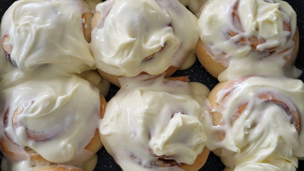 Six buns of cinnamon rolls covered with cream cheese frosting.