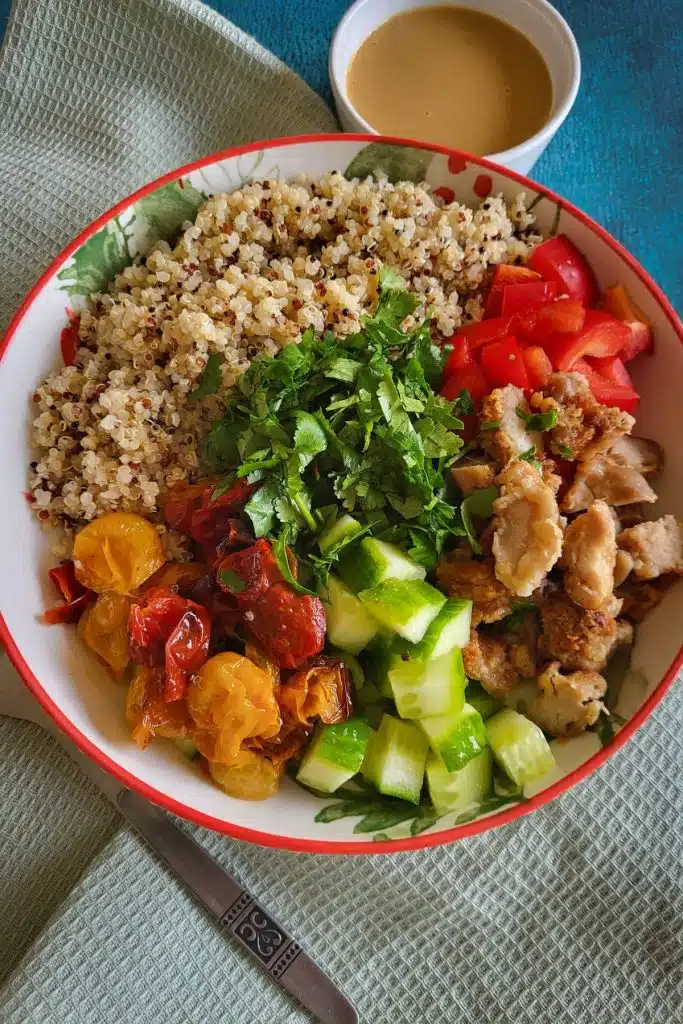 Ingredients of quinoa salad with roasted tomatoes arranged in a large round bowl.